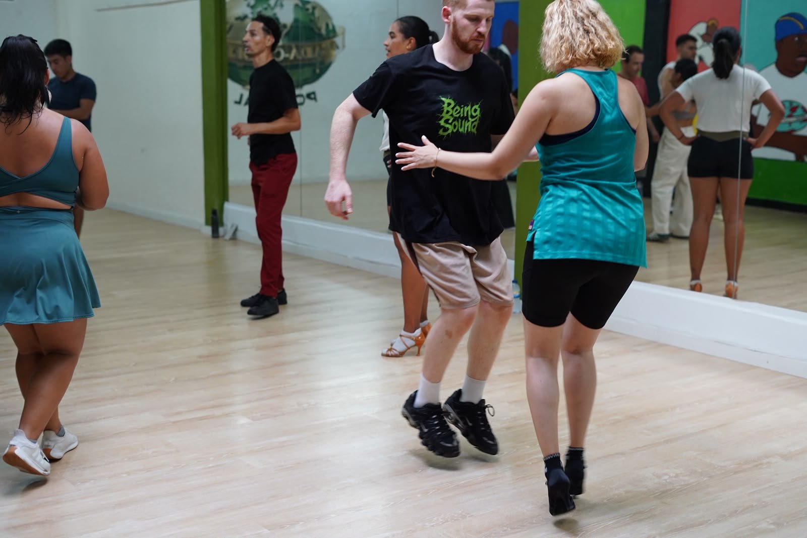 Participantes a praticar passos a pares num estúdio de dança, num workshop anterior